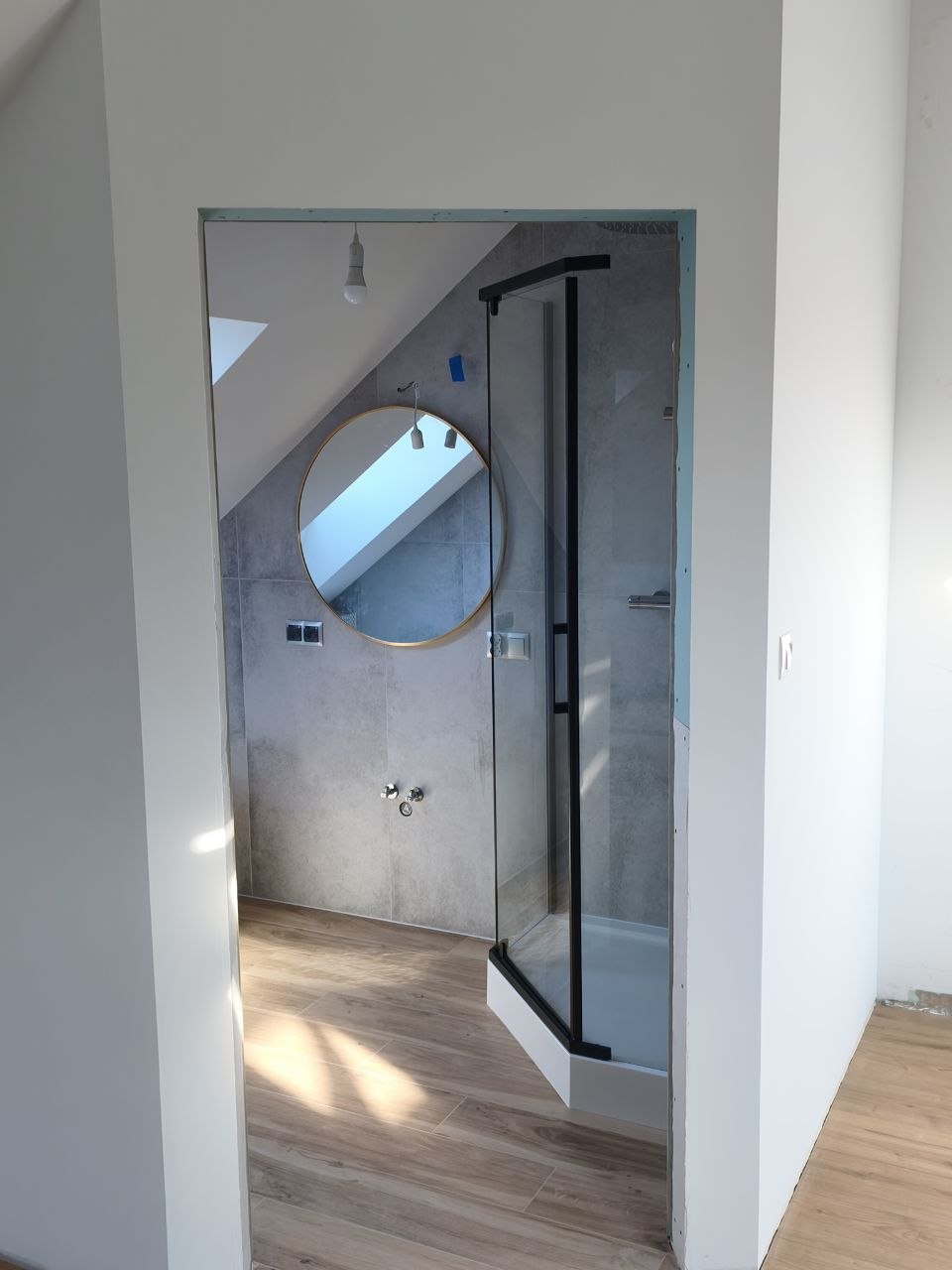 Kabina walk-in i okrągłe lustro w łazience na poddaszu