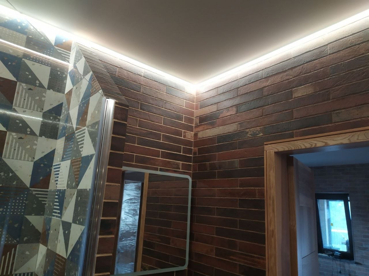 Łazienka z płytkami patchwork, cegłą dekoracyjną i podświetleniem LED